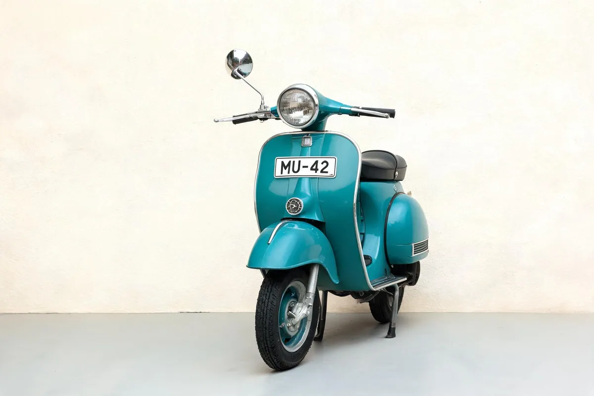 Input photo: a teal vintage scooter with number plate MU-42 against a cream plaster wall.