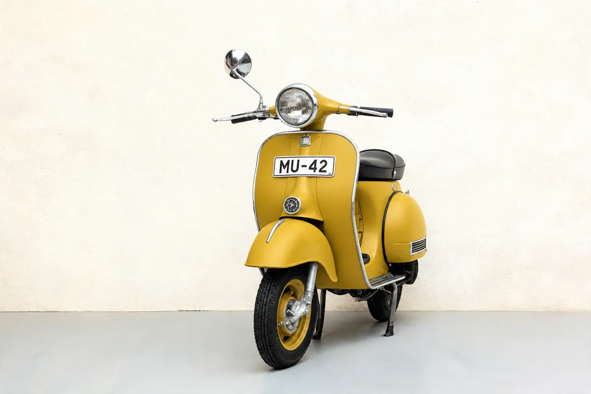 The edit: the same scooter in matte mustard yellow, with the chrome, the MU-42 plate, the wall and the shadow unchanged.